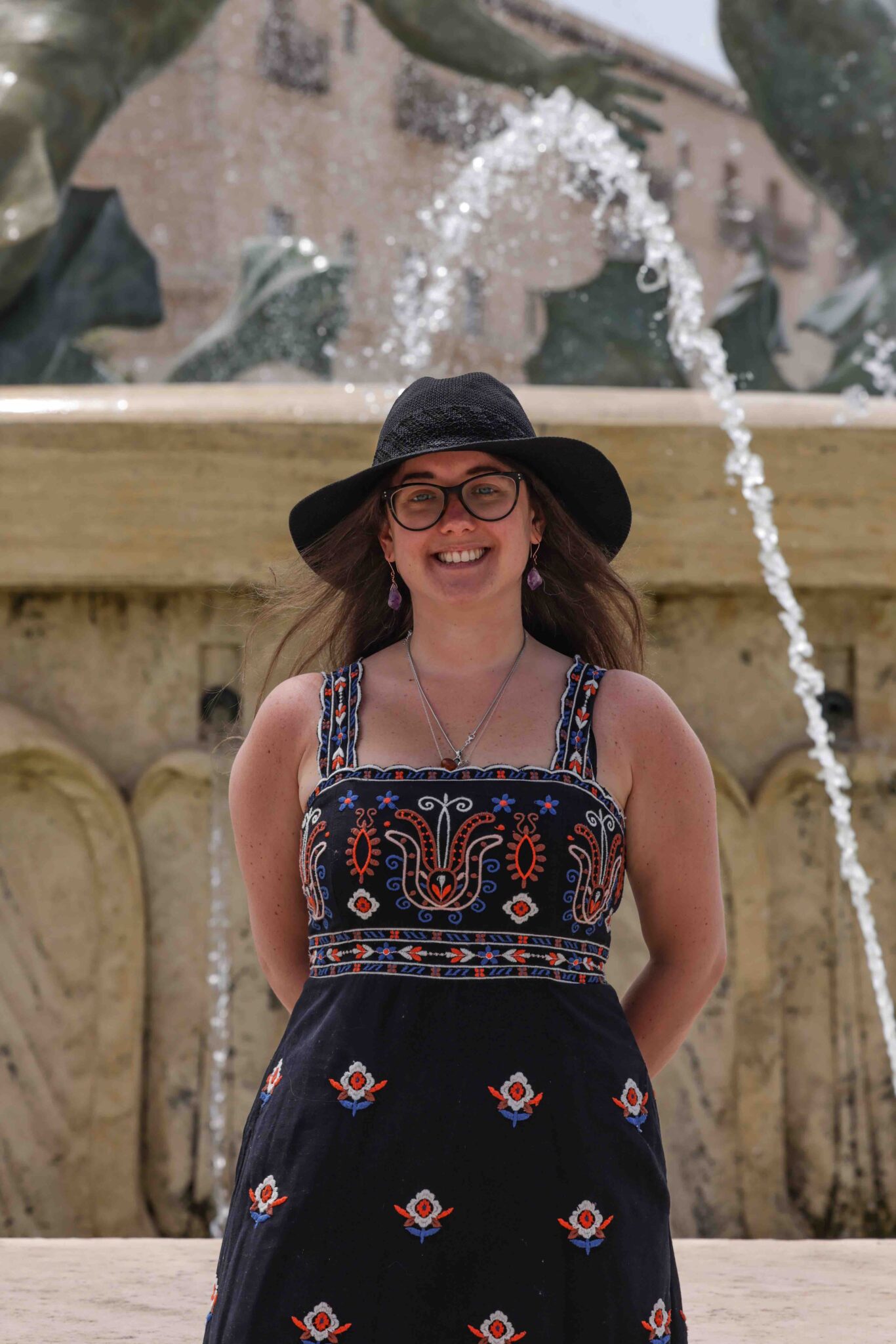 Travel writer and photographer, Jade Braham, is standing in front of a fountain in Malta.