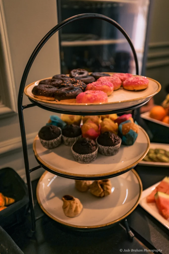There are doughnuts and muffins on a three-tiered plate.