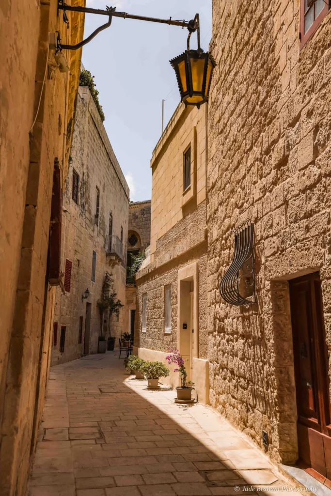 There are tables, chairs and street lamps down the alleyways in Mdina.