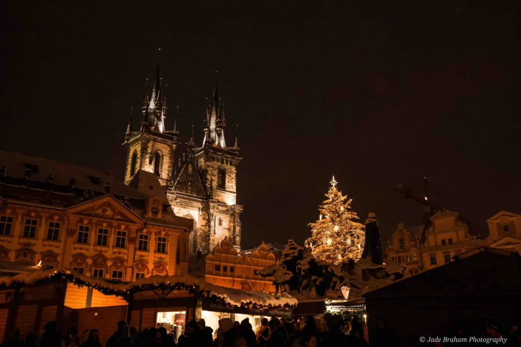 Prague Cathedral in the Old Town is lit up with lights and it's nighttime. 