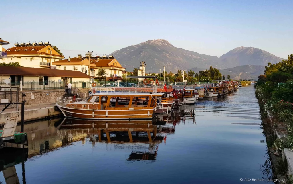 There are many boats docked in the river going through Çalis. 