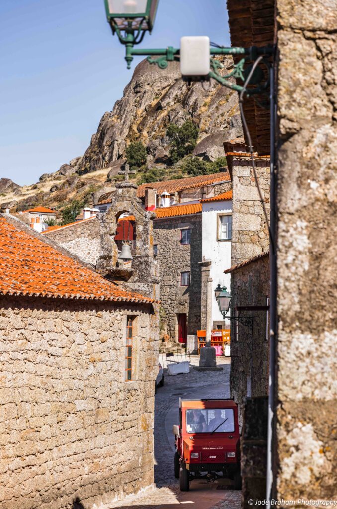 A tiny vehicle is driving down the cobblestone streets of Monsanto.