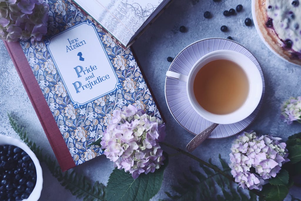 Elegant flatlay featuring a tea cup, hydrangeas, and the book 'Pride and Prejudice'.